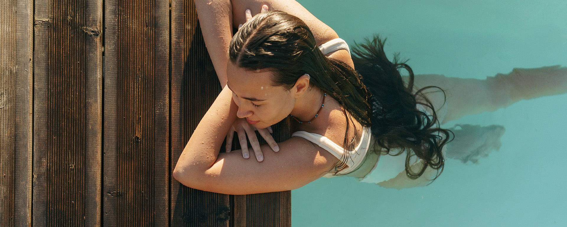 Frau im Pool, genießt das Wasser und die warme Sonne.